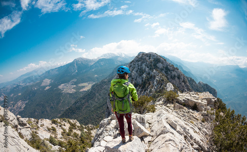 Woman climber with a backpack and a helmet in the mountains. A girl with a backpack walks along a mountain range. adventure and mountaineering concept.