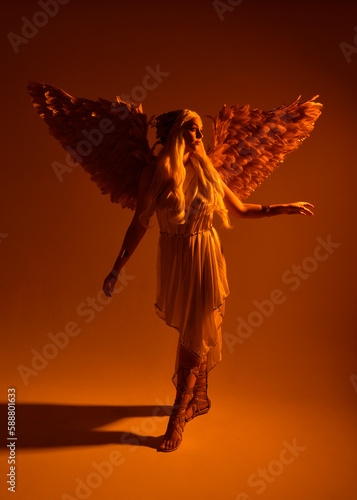 Full length portrait of beautiful blonde woman wearing a fantasy goddess toga costume with feathered angel wings. isolated on white studio background