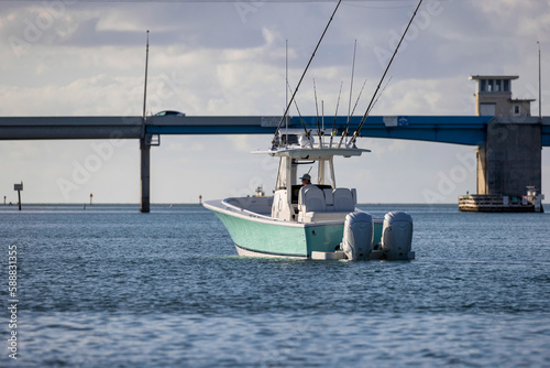 Center console fishing boat headed toward a bridge.