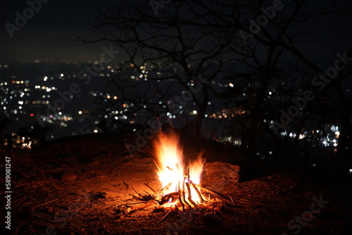 Bonfire on a hill overlooking a city.