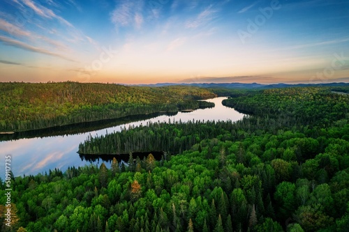 River in a green field under cloudy sky at sunset in Quebec, Canada