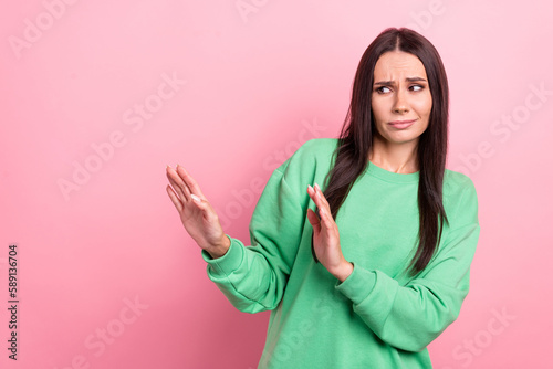 Photo of young stressed woman brunette hair wear green sweatshirt hands restriction discrimination against feminism isolated on pink color background