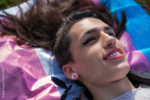 Overhead shot of a transsexual woman lying on the multicolored trans flag. We activate LGTBIQ+