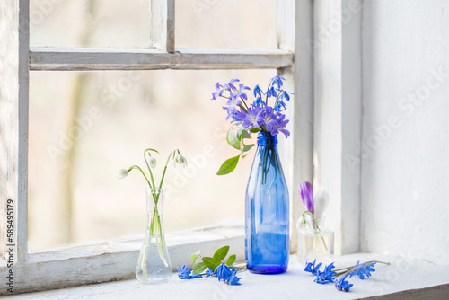 spring flowers in glass bottke on old window