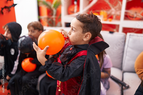 Group of kids wearing halloween costume inflating balloons at home