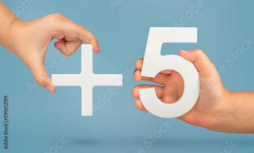 Plus five, plus size, add five concept. White number 5 with a plus in hand on a blue background close-up.