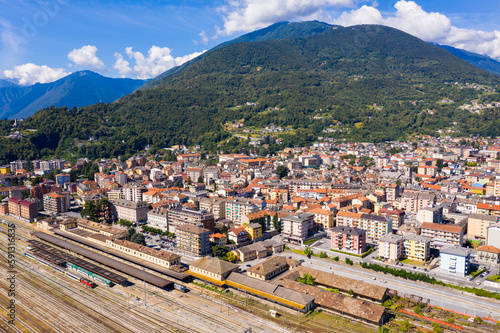 General view of Domodossola city at foot of green Italian Alps in sunny summer day looking out over railway station, Piedmont.