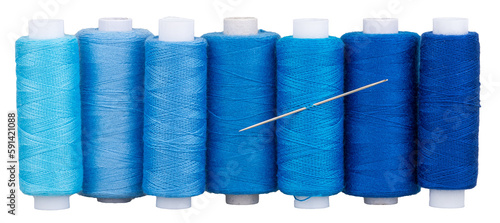 Many spools with blue thread and needle for sewing, supply for sewing, isolated objects 