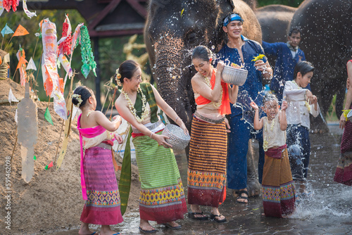 Tourist Asian people wearing traditional Thai dresses are happy to play splashing water during Songkran festival for travel a funny happy holiday in popular culture Thailand.