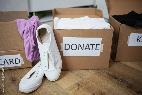 Close up clothes being sorted into of boxes Keep, Discard, Donate categories white sneaker. Zero Waste, recycling, sustainable. Decluttering and aleaning up closet or wardrobe