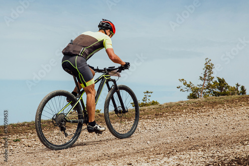 athlete cyclist riding mountain bike uphill, biking on gravel road, cycling competition