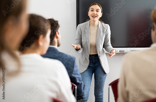 Young female tutor teaching students in college classroom