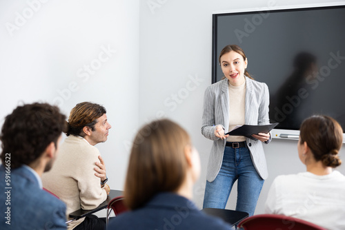 Young female professor explaining subject to classroom full of students