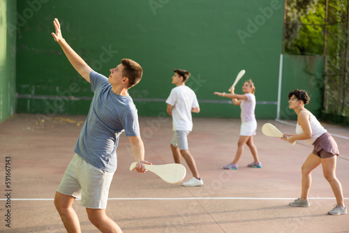 Caucasian teenage boy in sportswear playing paleta fronton on outdoor court