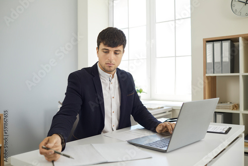 Business man on online meeting with clients writing making notes during conversation in laptop sitting at desk in office. Modern way of doing business, communicating customers online communication.