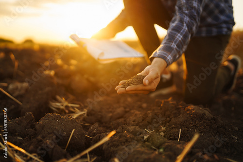 Farm owner checks the quality of the soil with his hands with a tablet and checks the fertility before sowing. Horticulture and agriculture concept.