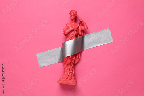 Antique statue of venus fixed with adhesive tape on a pink background. Conceptual pop, contemporary art, minimalist still life