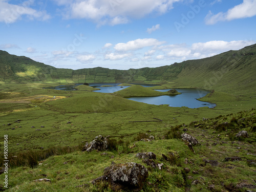 General view of the volcanic crater called Caldeirão, in its interior a lagoon is formed. In the foreground some rocks. Corvo Island, Portugal.
