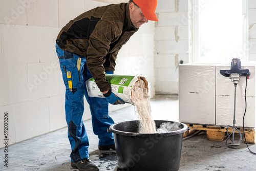 Construction work. Adding dry mortar mixture into clear water to make a mortar.