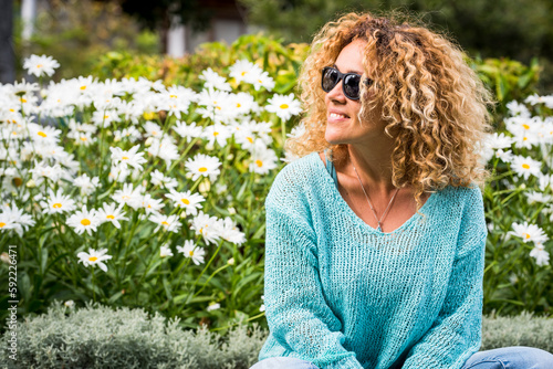 Vacation spring time season people concept lifestyle. Happy young woman smile and have outdoors leisure activity alone at the park with blossom daisy flowers in green natural background. Curly hair
