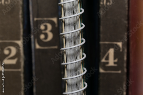 A spring-loaded notebook among old brown book volumes, close-up macro view