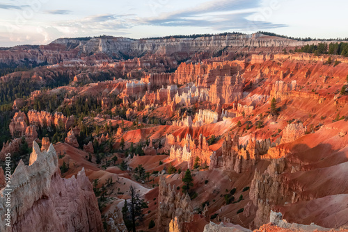 Panoramic aerial morning sunrise view on sandstone rock formations on Navajo Rim hiking trail in Bryce Canyon National Park, Utah, USA. Golden hour colored hoodoo rocks in unique natural amphitheatre