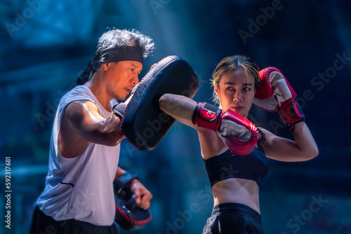 Female kickboxing training with male trainer gives self-defense classes to female fighter at GYM. Asian beautiful young woman exercise with trainer at boxing gloves, uppercut short, boxing, training