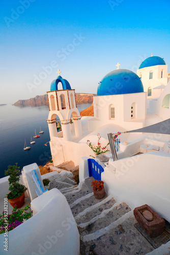 traditional greek village Oia of Santorini, with blue domes and stairs against sea and caldera with flowers, Greece, web banner format, toned