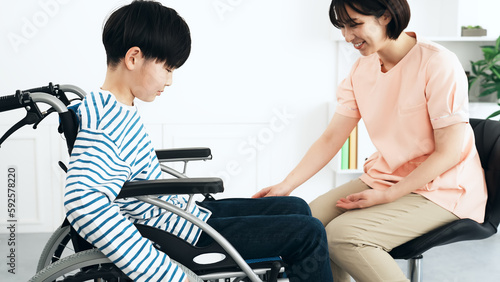 車椅子に乗った男の子を診察する看護師 医師