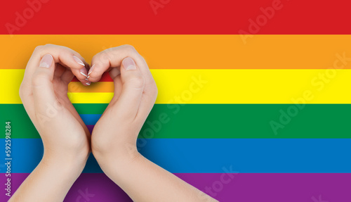 Female hand holding heart with LGBT flag