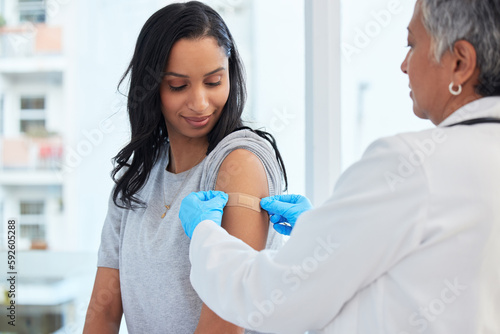 Healthcare, woman and doctor with plaster, vaccination and consultation in a hospital, cure and disease. Female patient, client and medical professional with care, vaccine and injection for safety