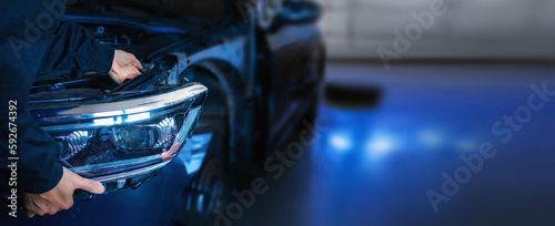Mechanic changing car headlight in a workshop