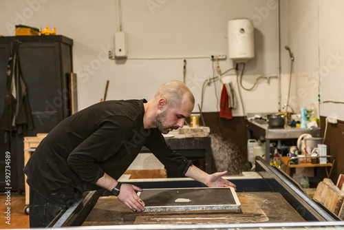 The artist placing a Lithographic limestone on a lithographic press or rolling press used for creating lithography in an art workshop.