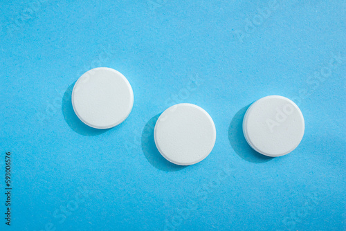 White soluble tablet pills isolated on a blue background. Top view, flat lay. Copy space for text.