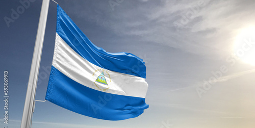 Nicaragua national flag cloth fabric waving on beautiful sky grey Background.