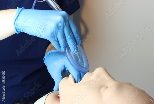 Laryngeal mask airway (LMA) Bering inserted in a simulated patient airway by a health care professional wearing gloves and surgical scrubs 
