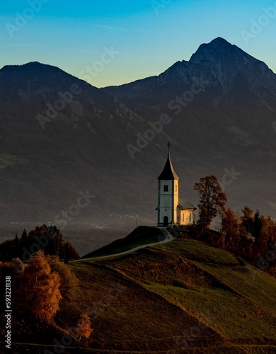 Vertical shot of The Church of St. Primoz and Felicijan on an evergreen hill in Jamnik, Slovenia