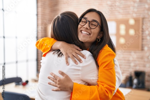 Two women business workers hugging each other at office