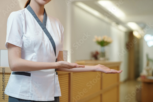 Cropped image of spa salon receptionist welcoming clients inside