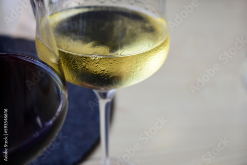 Glas mit Weißwein und Ausschnitt eines Rotweinglases mit Tau