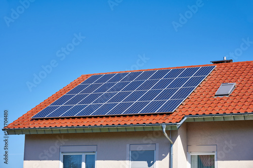 Solarzellen auf rotem Hausdach vor blauem Himmel