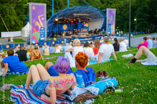 Audience sitting on plaids in park during concert