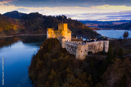 Picturesque aerial view of medieval Niedzica Castle on hilltop on banks of Lake Czorsztyn at twilight, Poland