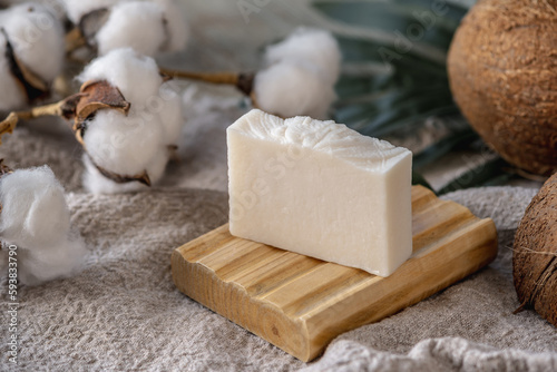 A piece of handmade white natural soap on a wooden soap dish