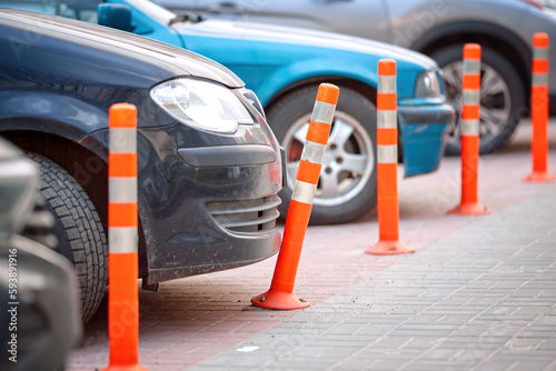 Car bumper and bent flexible plastic bollard in parking lot. Broken flexible traffic bollard. Car bumper and plastic barrier closeup. Car parked close to orange reflective bollard.