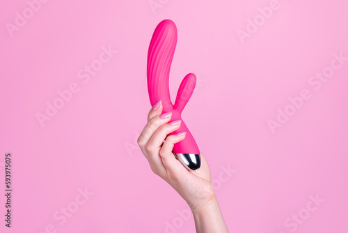 Pink sex toy rabbit shaped vibrator for women in female hand isolated on light pink background