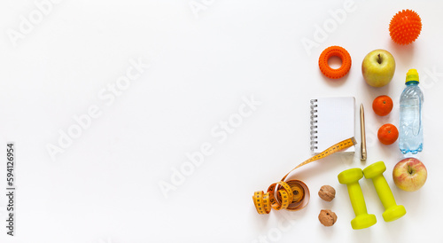 Healthy lifestyle concept. Diet plan. Activity and weight loss. Slimming for summer. Notepad, measuring tape, dumbbells, expander, massager, fruits, nuts and water on white background. Banner