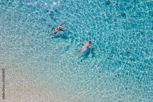 drone view at a men and woman swimming in the blue turqouse colored ocean of Koh Kradan island