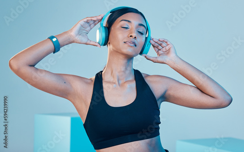 Headphones, fitness and woman isolated on blue background for workout, training or exercise music. Gen z, sports and biracial person listening on audio technology, mental health or wellness in studio