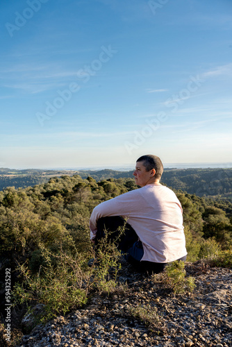 non-binary with very short hair enjoying a landscape in solitude, in the midst of nature, with her essence